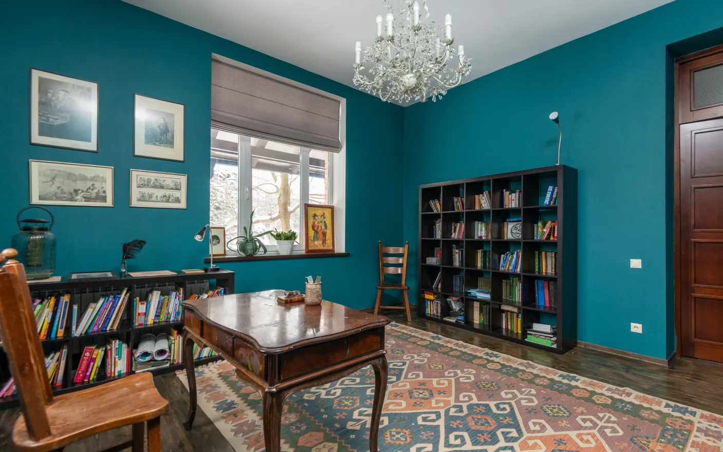 A freestanding table and chair beside a bookshelf against a plain wall, with nothing fixed to the wall itself.